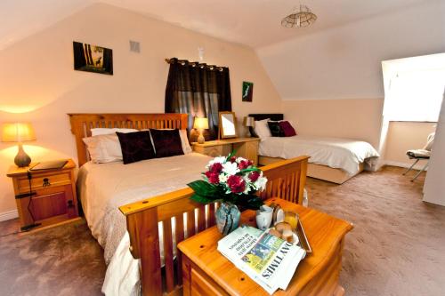 1 dormitorio con 2 camas y una mesa con flores en Strand's End House Rooms only, No Breakfast served, en Cahersiveen