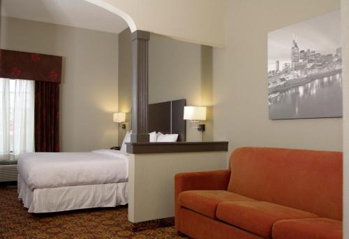 une chambre d'hôtel avec un lit et un canapé dans l'établissement Brentwood Suites, à Brentwood