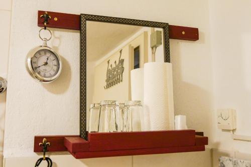 a mirror on a wall with glasses and a clock at ferienwohnung lispet in Neuötting