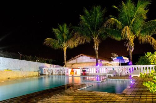 uma piscina com palmeiras à noite em Pousada Luz da Lua em Socorro