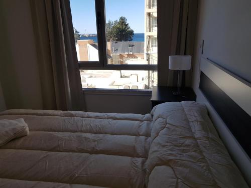 a bedroom with a bed and a large window at Departamentos Torre 1 in Puerto Madryn