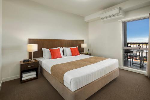 a bedroom with a large bed and a balcony at Quest Mildura in Mildura