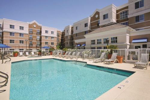 a swimming pool at a apartment complex with chairs at Hyatt House Pleasant Hill in Pleasant Hill
