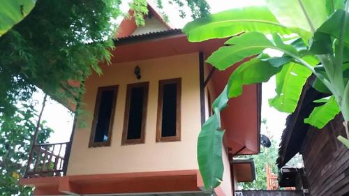 a house with red and white paint and green leaves at Heuan Na Khee in Udon Thani