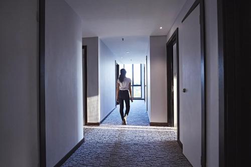 a woman walking down a hallway in a building at Meritin Hotel in Kuching