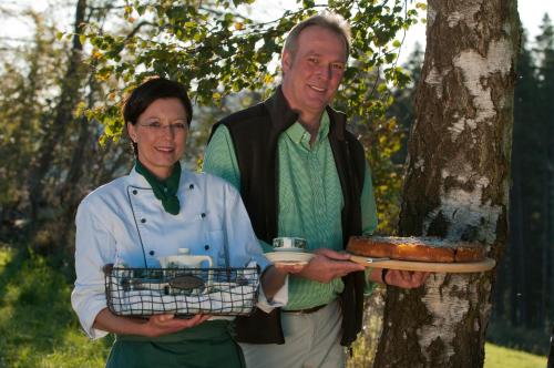 Ein Mann und eine Frau stehen neben einem Baum mit einem Kuchen in der Unterkunft Wüllner's Landgasthof in Schmallenberg