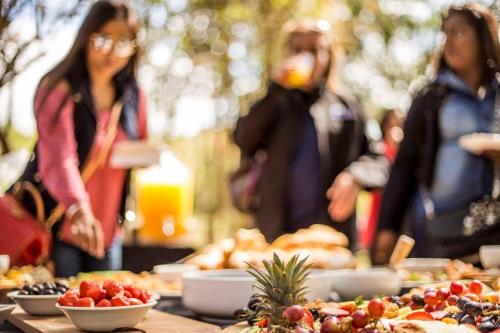 a table full of food with people in the background at Rain Farm Game Lodge in uMhlali