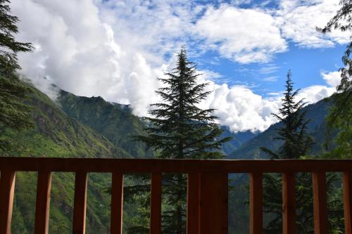 a view of the mountains from a wooden deck at Kudrat - A Boutique Homestay- Tirthan Valley in Banjār
