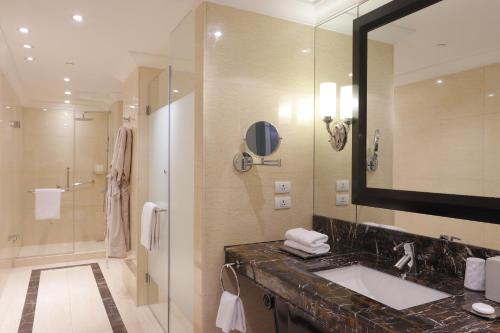 a bathroom with a sink and a mirror and a shower at Raffles Makati in Manila