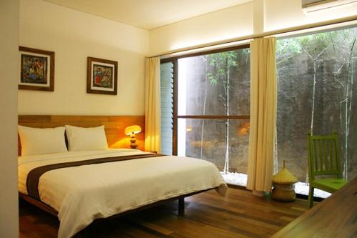 - une chambre avec un lit et une grande fenêtre dans l'établissement Rumah Turi Eco Boutique Hotel, à Solo