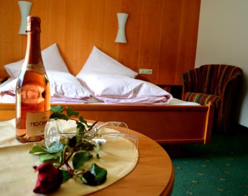 a bottle of wine on a table with a bed at Pension Vier Jahreszeiten in Saalbach-Hinterglemm