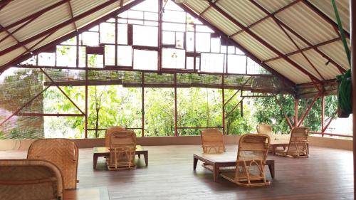 Großes Zimmer mit Stühlen, Tischen und Fenstern in der Unterkunft Rumah Turi Eco Boutique Hotel in Solo