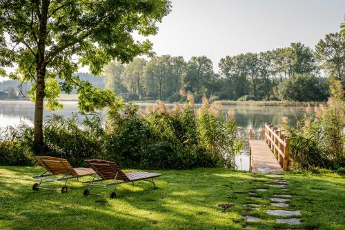 two chairs and a bench in the grass near a lake at Kloster Seeon in Seeon-Seebruck