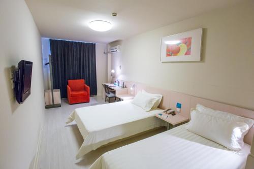 Cette chambre d'hôtel comprend deux lits et un fauteuil rouge. dans l'établissement Jingjiang Inn Beijing Guang'anmen, à Pékin
