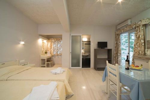 a bedroom with two beds and a desk and a room at Athena Apartments in Agia Galini