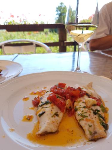 a white plate with a piece of fish on a table at Hotel Caneo in Fossalòn