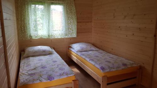 1 dormitorio con 2 camas y ventana. en Gościniec Mazurek , Domek drewniany 1 en Giżycko