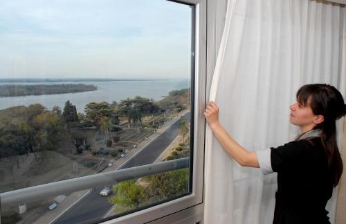 a woman is looking out of a window at Maran Suites & Towers in Paraná