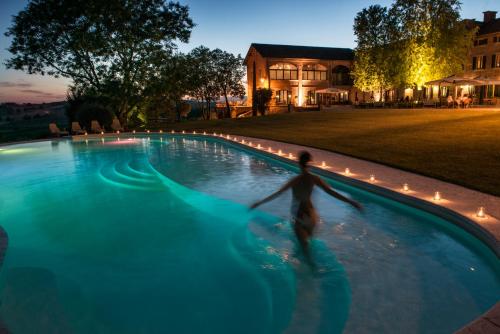 a person in a swimming pool at night at Tenuta Montemagno Relais & Wines in Montemagno
