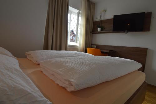 a bedroom with a bed with a television and a window at Pension Elisabeth - Rooms & Apartments in Salzburg