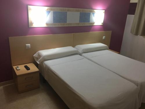 a bedroom with two beds and a small table at Hostal Ducal in Gandía