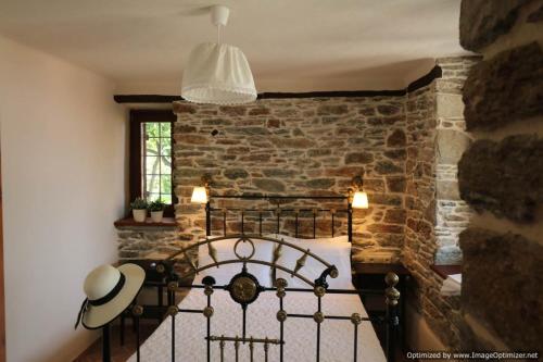 a bedroom with a bed with a stone wall at House Smaragdi in Agios Ioannis Pelio