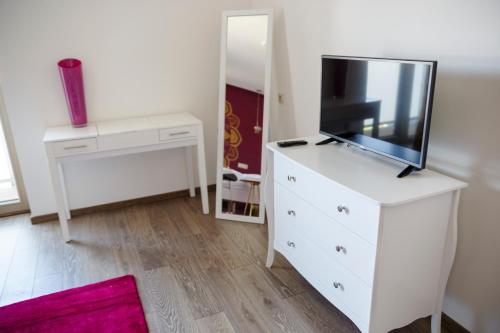 a white dresser with a tv on top of it at Penzión v Inom Svete in Žilina
