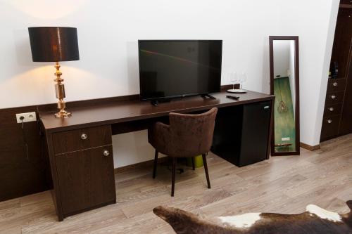 a room with a desk with a television and a chair at Penzión v Inom Svete in Žilina