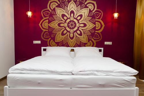ein Schlafzimmer mit einem weißen Bett mit einer Mandala-Wand in der Unterkunft Penzión v Inom Svete in Žilina