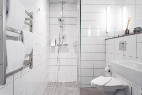 a white bathroom with a shower and a toilet at Biz Apartment Hammarby Sjöstad in Stockholm