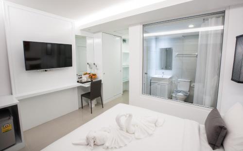 a white bedroom with a white bed and a television at Chiangmai Midpoint Activity Hostel in Chiang Mai