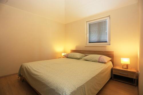 a bedroom with a bed with two lamps and a window at Apartment Pa Ve in Murter
