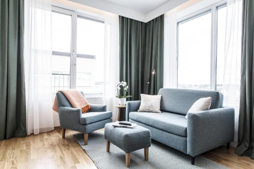 a living room with two chairs and a couch and a stool at Biz Apartment Hammarby Sjöstad in Stockholm