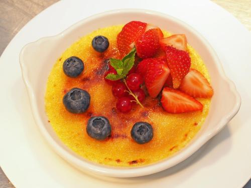 a white plate with a bowl of food with strawberries and blueberries at Hotel Restaurant Schute in Emstek