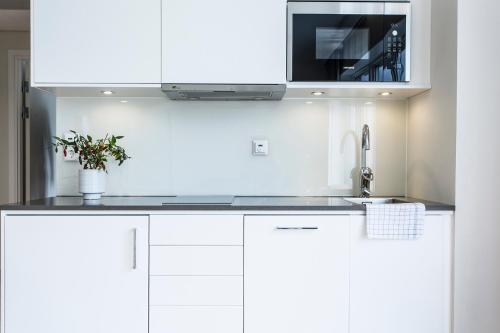 a white kitchen with a sink and a microwave at Biz Apartment Hammarby Sjöstad in Stockholm