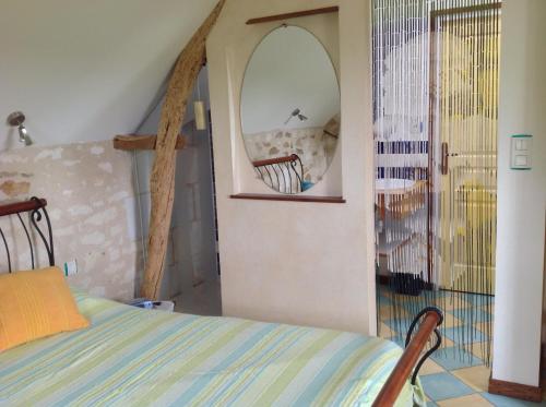 - une chambre avec un lit et un miroir rond dans l'établissement Maison de vacances La Haute Cormerie, à Le Thoureil