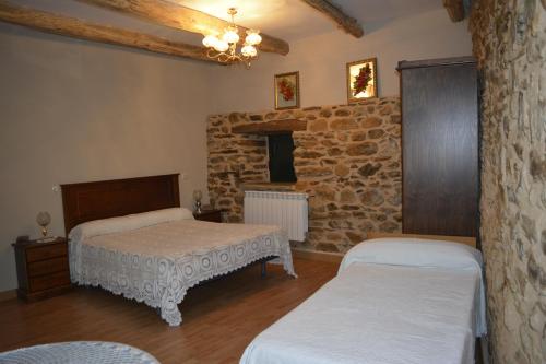 1 Schlafzimmer mit 2 Betten und einer Steinmauer in der Unterkunft La Casa de Rosa in Filiel