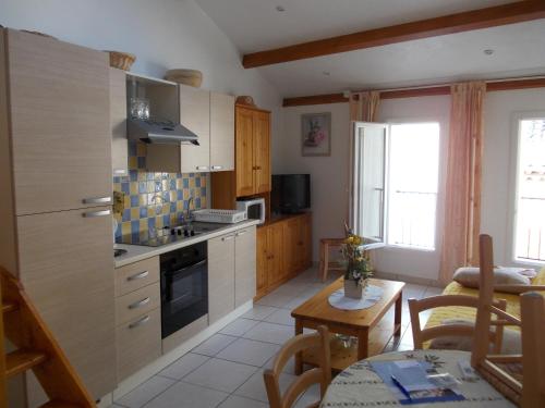 una cocina con armarios de madera y una mesa en una habitación en Studios Castellane, en Castellane