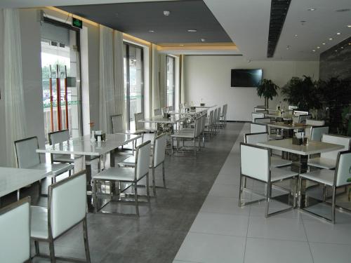 a dining room with tables and white chairs at Jinjiang Inn Beijing Liangxiang Nanguan Subway Station in Fangshan