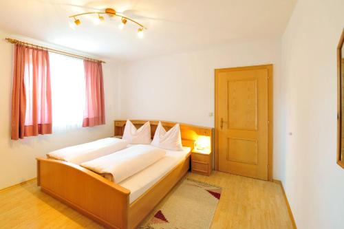a bedroom with a bed with white sheets and a window at Haus Goldeggblick in Goldegg