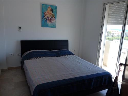 um quarto com uma cama num quarto com uma janela em Appartement Vue Sur Mer Turquoise em Mahdia