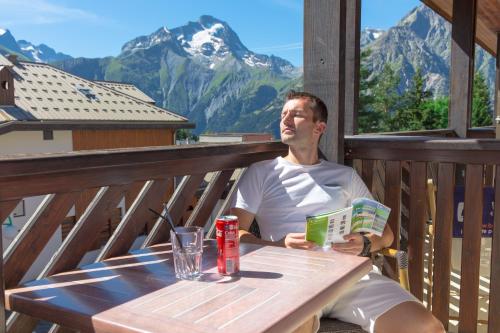 a man sitting at a table with a glass of beer at Hotel Les Flocons in Les Deux Alpes