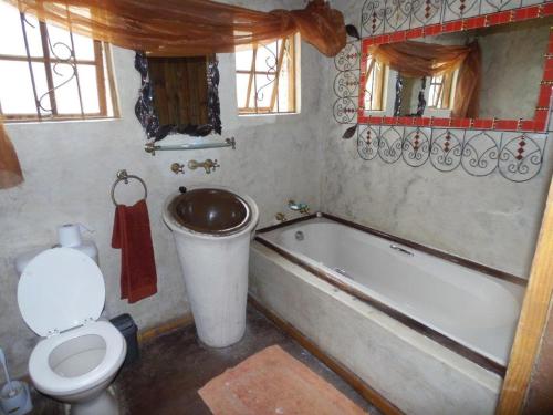 a bathroom with a toilet and a tub and a sink at Hazyview Country Cottages in Hazyview