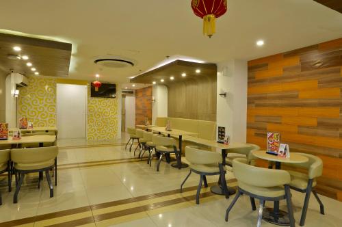 a restaurant with tables and chairs in a room at Hotel 99 Monumento in Manila