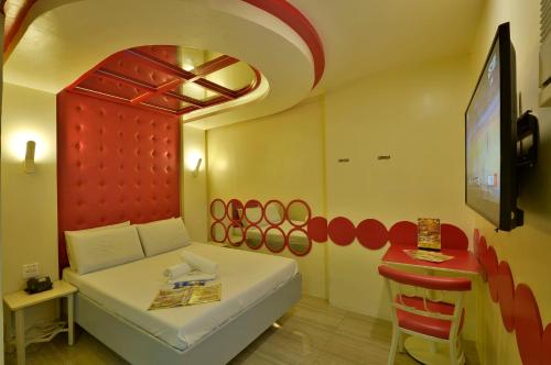 a room with a bed and a table and a tv at Hotel 99 Monumento in Manila
