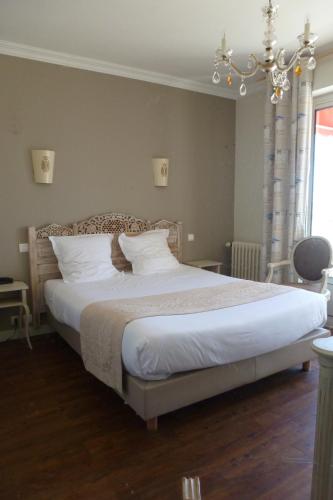 a bedroom with a bed with white sheets and a chandelier at Family Golf Hotel in Royan