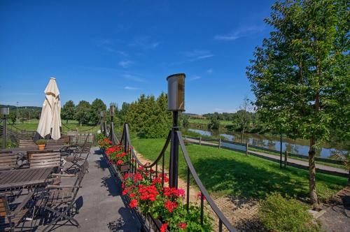 a row of benches with flowers and an umbrella at Gastwirtschaft & Hotel Hallescher Anger in Naumburg