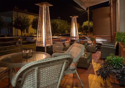 a patio with wicker chairs and tables at night at Hotel Capitol in Biała Podlaska