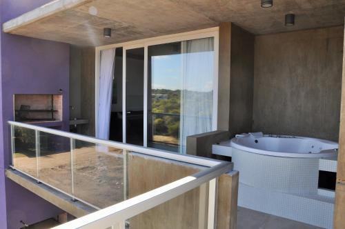 baño con bañera y lavabo y ventana grande en CÁFILA Apart & Spa en Las Gaviotas