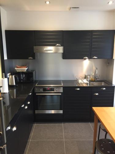 une cuisine avec des armoires noires et un four en acier inoxydable dans l'établissement Studio Québec Vue Mer, à Saint-Malo